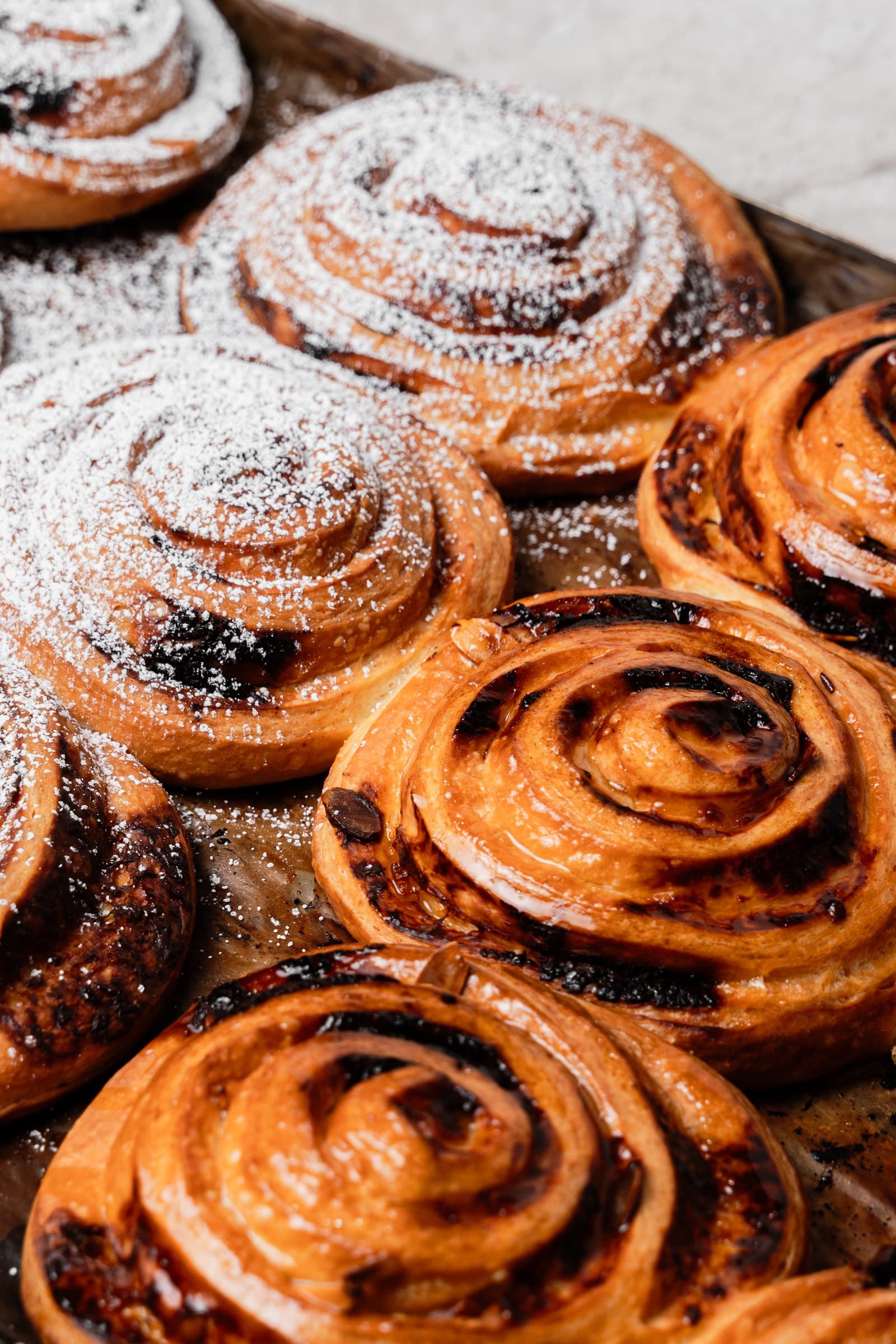 A tray of scrolls fresh from the oven, half dusted with icing sugar