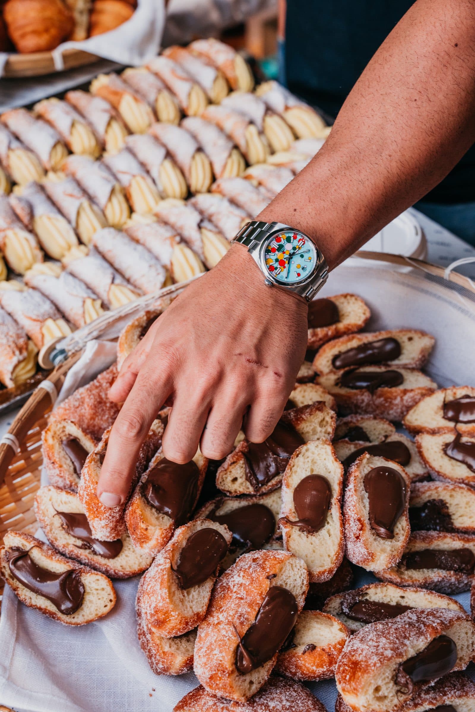 A hand reaching for a pastry from a son of a baker catering spread