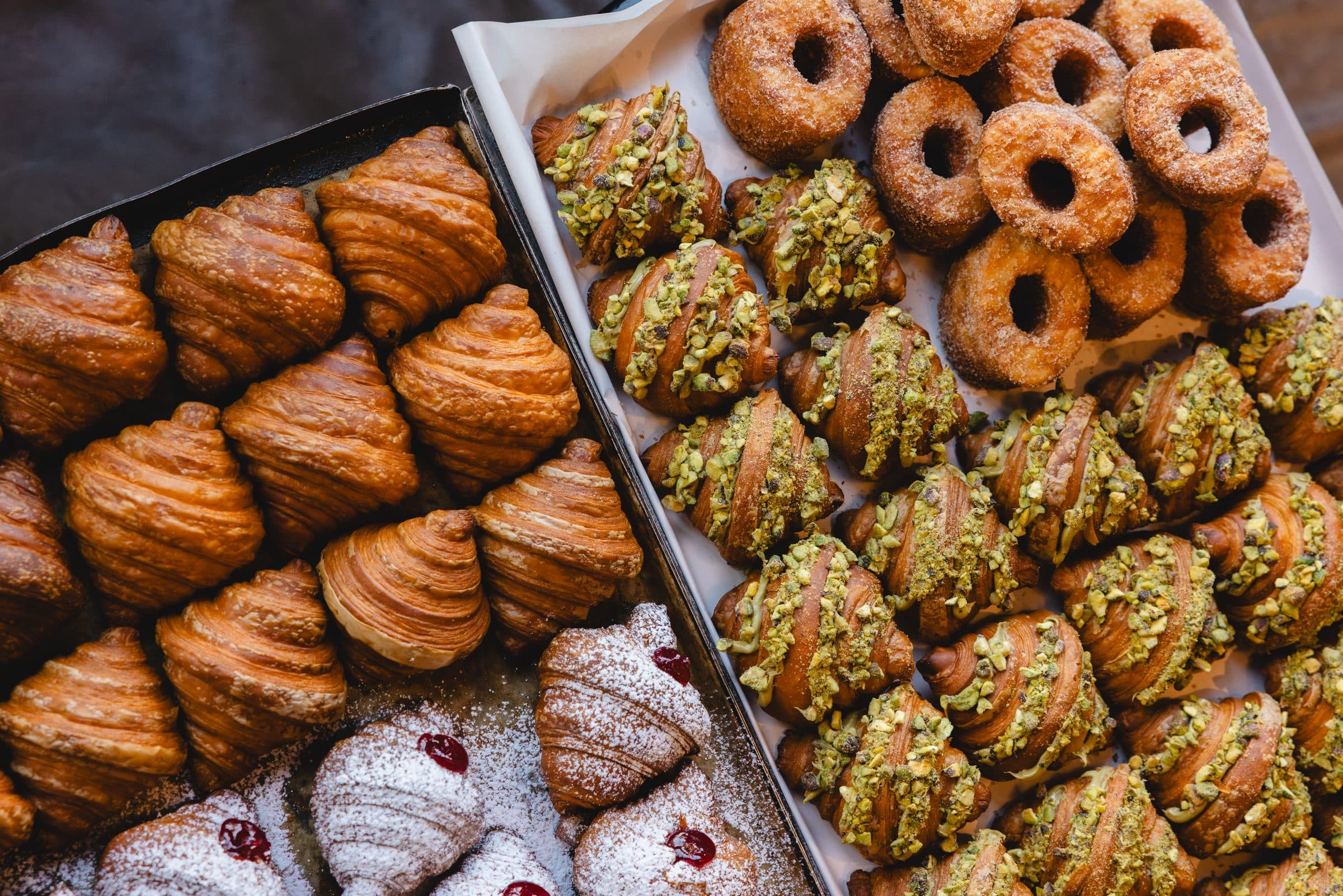 Trays of mini croissants, pistachio pastries and doughnuts
