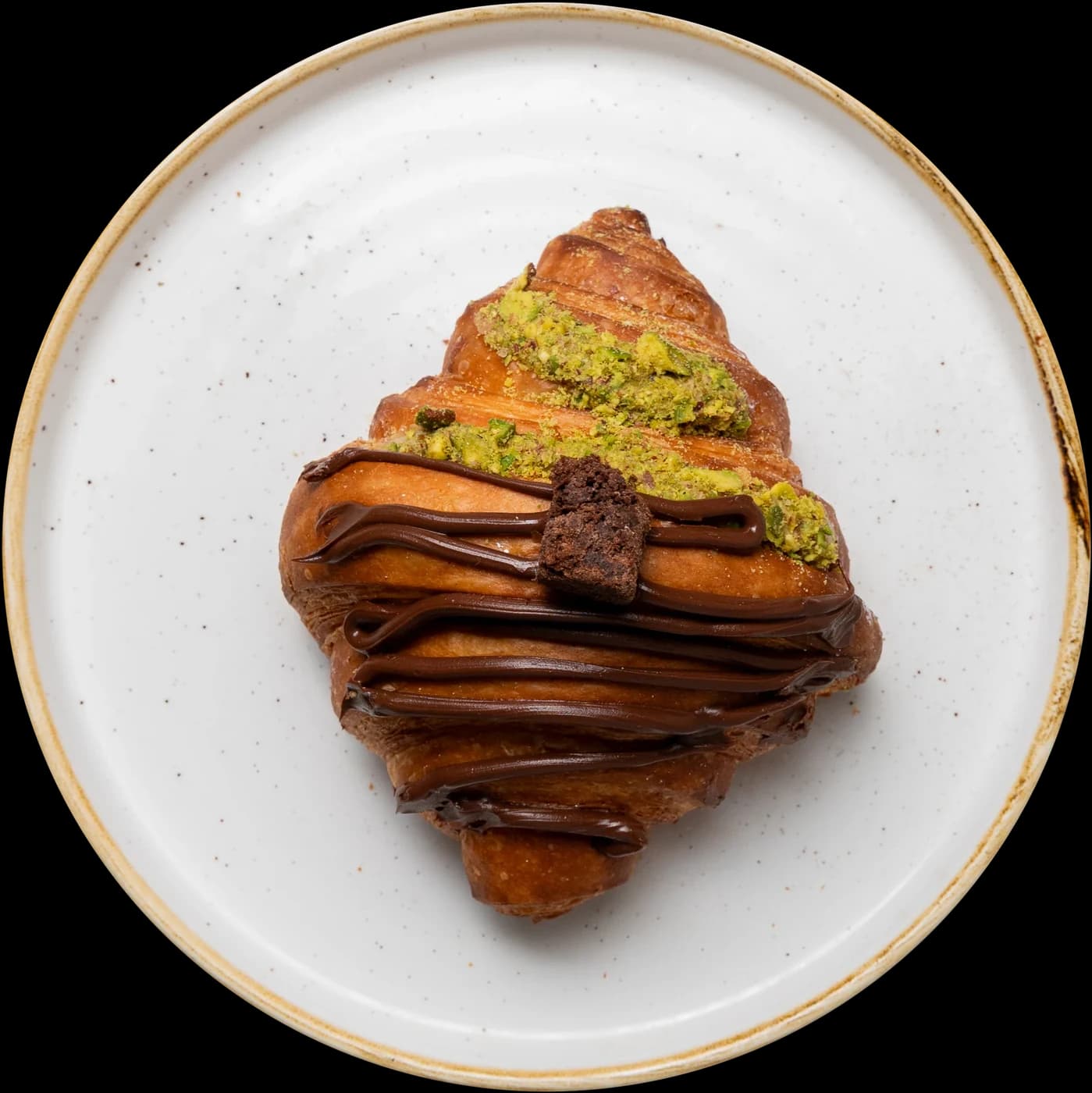 Croissant with chocolate drizzle and pistachio
