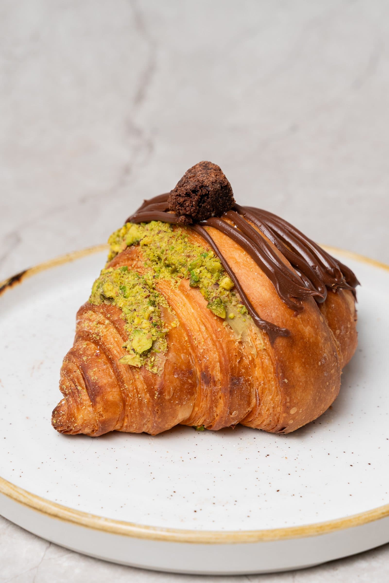 Croissant topped with chocolate and crushed pistachio