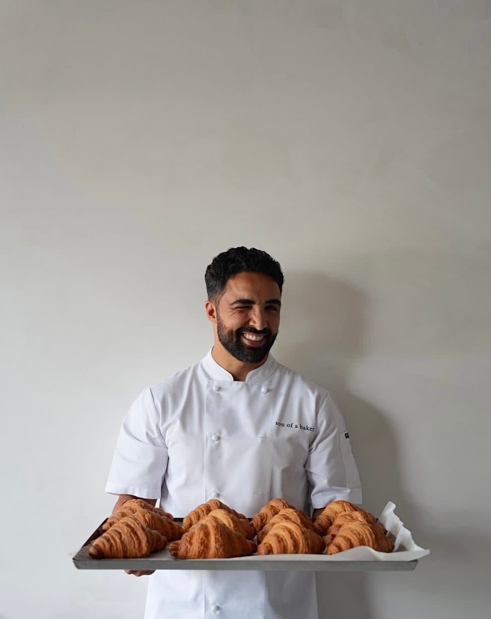 The son of a baker, holding a tray of fresh croissants